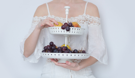 photo of young woman holding stand with fruits on the wonderful white background