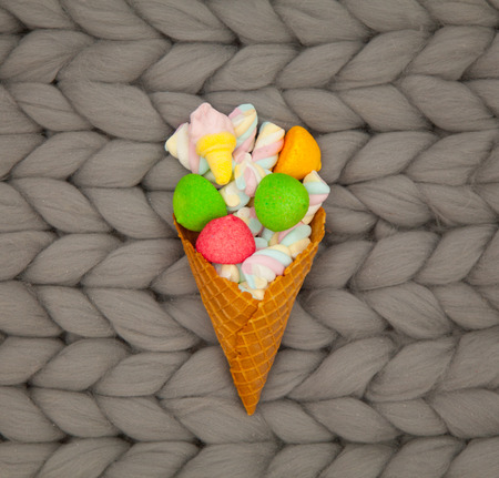 photo of colorful marshmallows and waffle cone on the wonderful grey blanket backgroundの写真素材