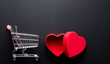 photo of beautiful shopping cart and heart shaped box on the wonderful black studio backgroundの写真素材