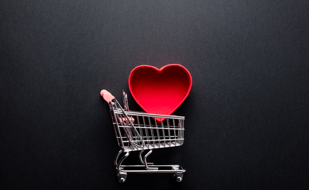 photo of beautiful shopping cart and heart shaped box on the wonderful black studio backgroundの写真素材