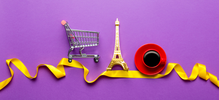 Cup of coffee and Eiffel tower toy with cart on violette backgroundの写真素材