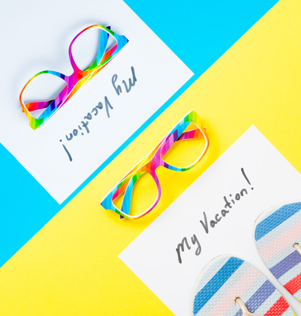 photo of sheet of paper My Vacation, colorful glasses and colorful Flip Flops on the wonderful yellow studio backgroundの写真素材