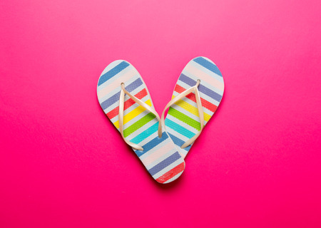 Above view at multicolor striped flip flops in pink backgroundの写真素材