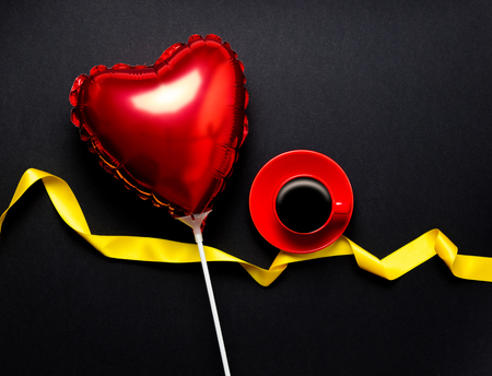 Cup of coffee and heart shape balloon on black backgroundの写真素材