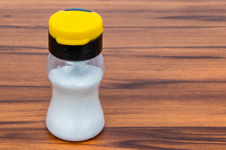 White salt shaker with colored cap Isolated on wooden Backgroundの写真素材