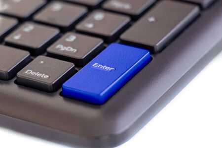 Enter key highlight with blue color on keyboard with finger pressing button on white background, selective focusの写真素材