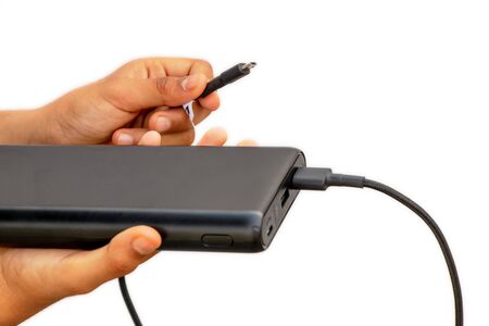Hands showing battery charger (Power bank) with usb charging cable white isolated on a white backgroundの写真素材