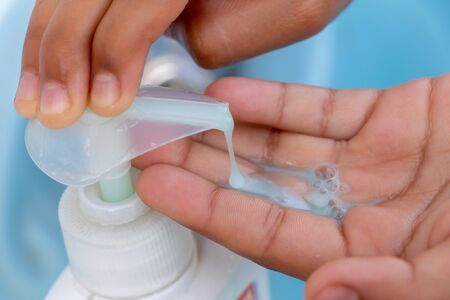 Female hand takes liquid soap from a soap dispenser to wash hands at the sinkの写真素材