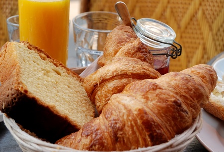 close-up of french breakfast with croissants and cake on little basket with strawberry jam and orange juice on background の写真素材