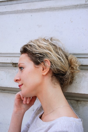 Outdoor portrait of a young caucasian blond woman against wall for background 