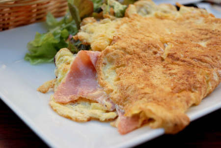 English breakfast with omelet and ham in white plateの写真素材