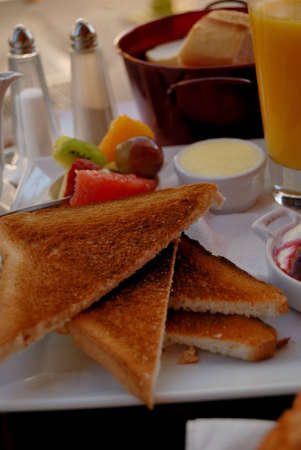Isolated breakfast with fruits, butter,  toast and strawberry jam  Orange juice is on background 