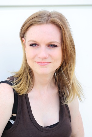 portrait of young blond smiling woman against white wall in the street のeditorial素材
