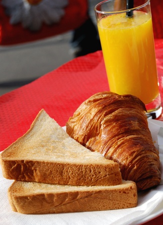 isolated croissants with toast and orange juice on red table 