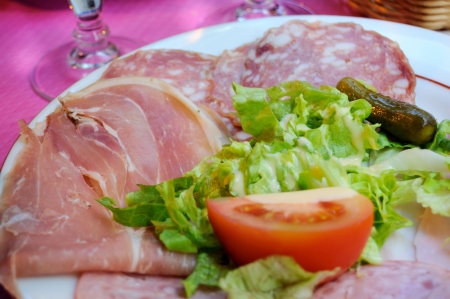 close up of plate of cold meat with ham, rosette, lettuce and tomato  の写真素材
