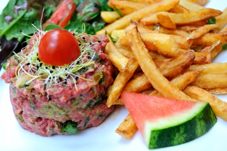 close-up of isolated classic steak tartare with frenh fries and watermelon on white plate の写真素材