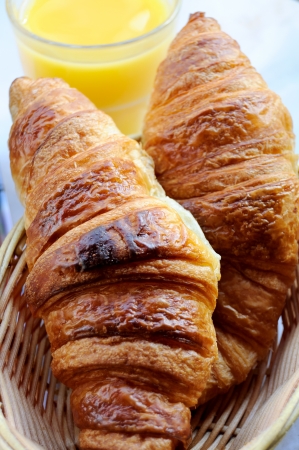 close-up of isolated croissants in basket with orange juice in backgroundの写真素材