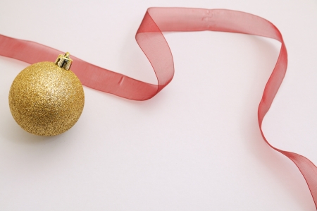 Isolated golden christmas bauble and red ribbon in white backgroundの写真素材