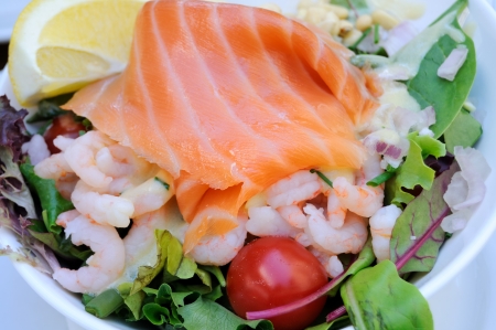 A seafood salad with smoked salmon, fresh lettuce, prawn, onion, tomato and lemonの写真素材