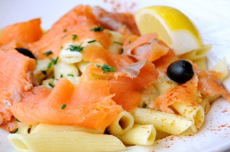 close-up of plate of penne and smoked salmon with lemonの写真素材