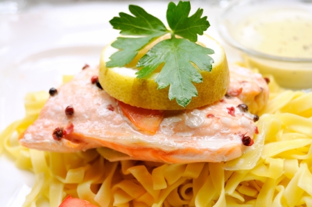 close-up of plate of steamed salmon with past and lemon on the topの写真素材