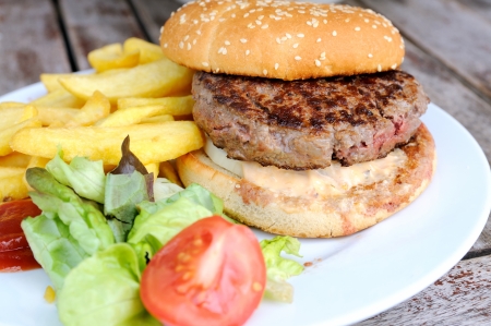 isolated delicious american cheese burger with french fries and fresh lettuce in tableの写真素材