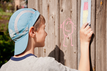 child drawing a chalk picture on wooden wallの写真素材