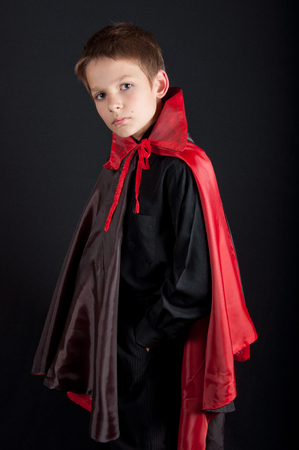 Boy dressed like vampire for Halloween party. Black and red clothes, black backgroundの写真素材