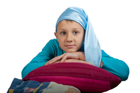 Boy in blue pajamas and sleeping hat  lays on pillow isolated on whiteの写真素材