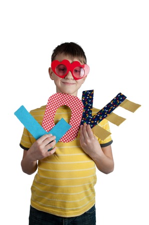 Cute young boy in red glasses with paper letters love in his hands isolated on white background.の写真素材