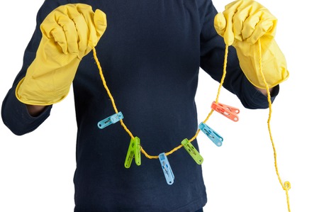 Human hands in rubber yellow gloves hold rope and clothespins on it. Isolated on whiteの写真素材