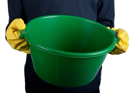 Human in dark-blue shirt and rubber gloves holds small green washbowl. Isolated on whiteの写真素材