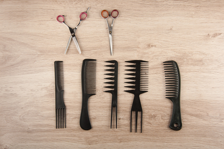 Professional hairstylist  instruments. Scissors, black comb,  brushes laying on the wooden table. Space for text.の写真素材