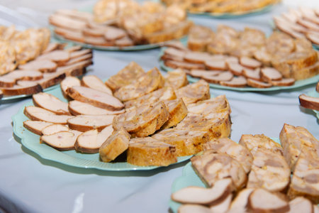 Different sliced sausages on blue plates staying on buffet table. Meat pieces on party. Selective focus. High quality photoの写真素材