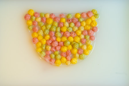 Top view on dry breakfast cereals, yellow, pink, green corn balls in milk. Crunchy bowl, healthy and fiber food concept. Breakfast time. High quality photoの写真素材