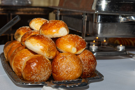 Stacked rolls, tasty baked buns on party table. Hanukkah food, selective focus. Tower of various...