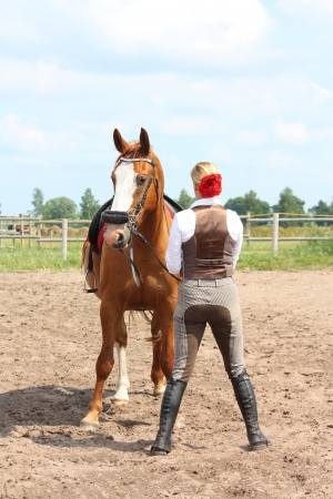 Beautiful young blonde woman and chestnut horse looking at each otherの写真素材