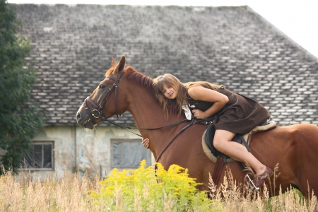 Young girl and chestnut horse portrait near the barn in summerの写真素材
