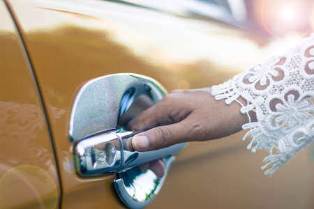 A woman's hand opening the car door for a road trip.