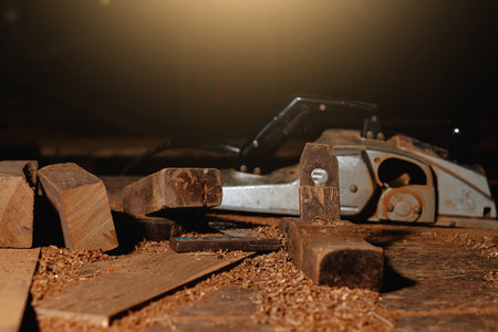 Close-up of a carpenter using a circular saw or a tool to cut wooden planks to make furniture in...