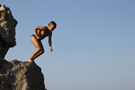 Alupka, Ukraine - August, 14, 2010. Unknown small boy prepared to jump into the sea from rock.のeditorial素材