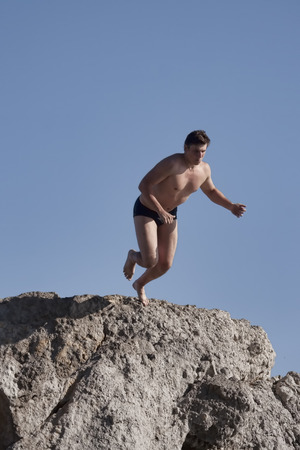 ALUPKA, UKRAINE - AUGUST 23, 2012: Unidentified young man runs up to jump off a cliff into the seaのeditorial素材