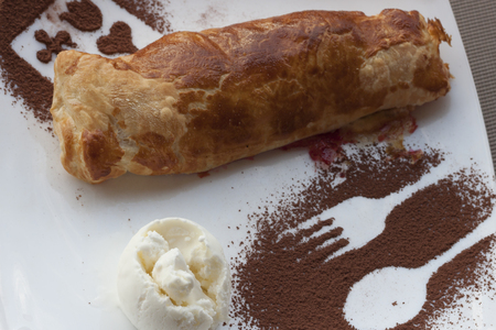 Cherry strudel with ice cream and chocolate. Confection of thin pastry rolled up around a fruit filling and bakedの写真素材