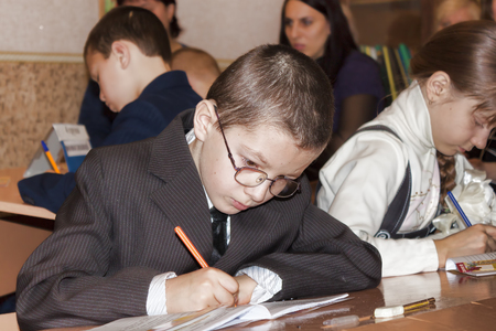 SLOVIANSK, UKRAINE - NOVEMBER 17, 2011: An unknown junior student at a desk writes something in a notebook at a lesson in one of the schools in Slovianskのeditorial素材