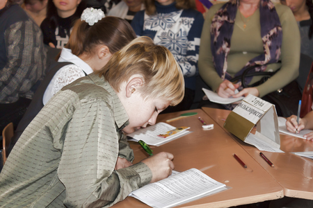 SLOVIANSK, UKRAINE - NOVEMBER 17, 2011: An unknown junior student at a desk writes something in a notebook at a lesson in one of the schools in Slovianskのeditorial素材
