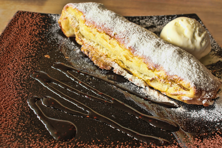 Apple strudel with ice cream and chocolate. Confection of thin pastry rolled up around a fruit...