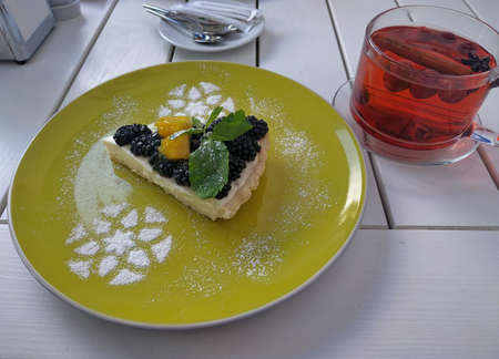 Berry tart with blackberries and orange. Decorated with mint leaves and powdered sugar patterns