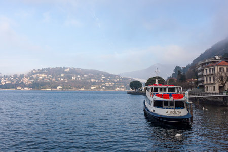 COMO, ITALY - FEBRUARY 25, 2023: View of Lake Como from the promenade. In the morning, mountains in fogのeditorial素材