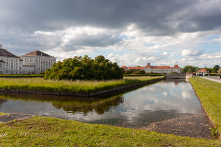 MUNICH, GERMANY - MAY 17, 2025: A wide-angle landscape view of the serene canal and expansive grounds of Nymphenburg Palace in Munich, Germany, on a partly cloudy dayの写真素材