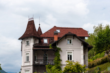 BLED, SLOVENIA - MAY 20, 2025: A grand, historic-looking building with a distinctive reddish-brown roof and multiple gables, located in the picturesque town of Bled.の写真素材